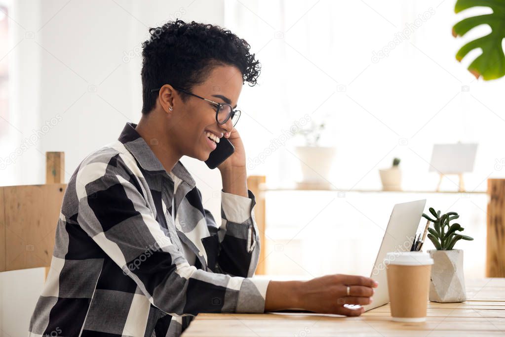 Smiling woman working using computer and phone in office