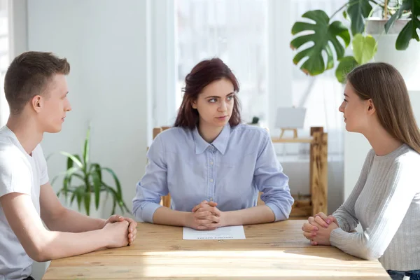 Three young people sitting at the desk in office — Stock Photo, Image