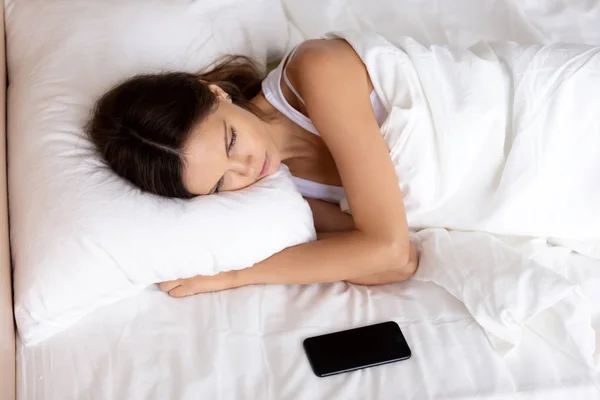 Nuori turhautunut nainen makaa sängyssä puhelimen kanssa tuntuu onnettomalta — kuvapankkivalokuva