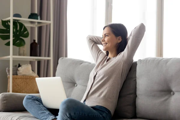 Zadowolony kobieta nachylając się na kanapie w domu odpoczynek z laptopa — Zdjęcie stockowe