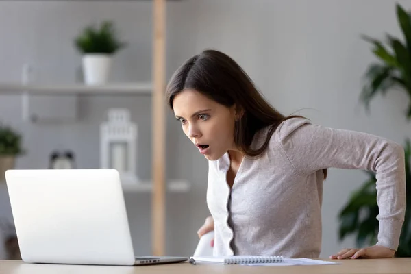 Шокована жінка, дивлячись на екран ноутбука, здивована поганими новинами — стокове фото