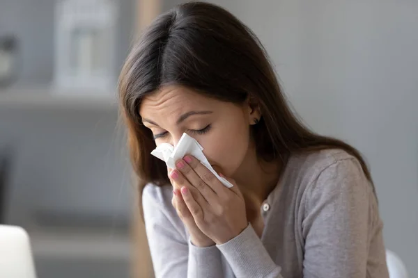 Sick young woman holding tissue and blowing her running nose — Stock Photo, Image