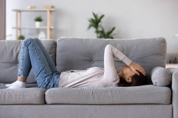 Повна довжина молодої жінки, що лежить на дивані, страждає від серцебиття — стокове фото