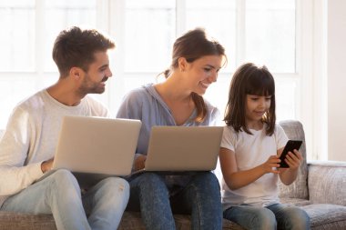 Aile içinde dijital cihazlar absorbe kanepede oturan gülümseyen