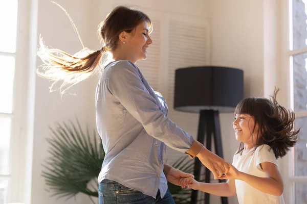 Moeder hand in hand met dochter dansen en springen thuis — Stockfoto
