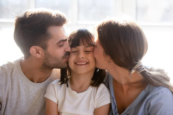 Feliz padres besar poco preescolar encantadora hija en mejillas — Foto de Stock