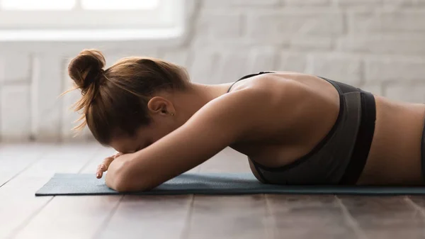 Mujer joven practicando yoga, acostada boca abajo, respirando, relajándose — Foto de Stock