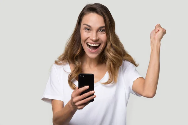 Opgewonden vrouw Holding smartphone voelt zich blij vieren overwinning — Stockfoto