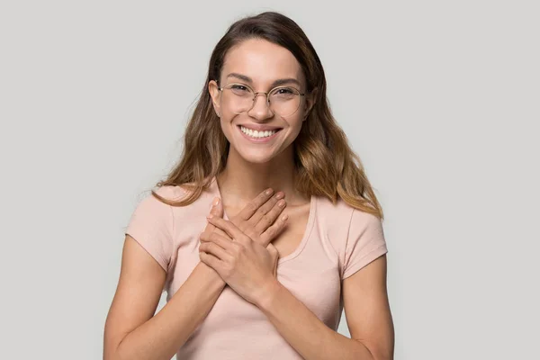 Headshot woman in glasses feels grateful holding hands on chest — Stock Photo, Image