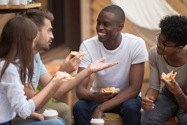 Multiracial happy friends laughing at joke eating pizza in cafe — Stock Photo, Image
