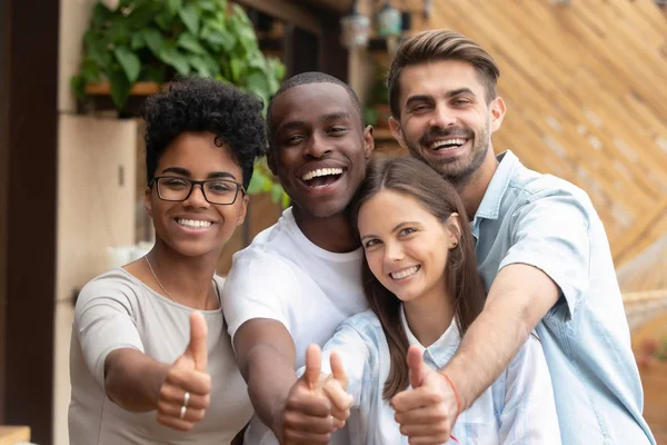 Happy multi-ethnic friends group showing thumbs up looking at camera