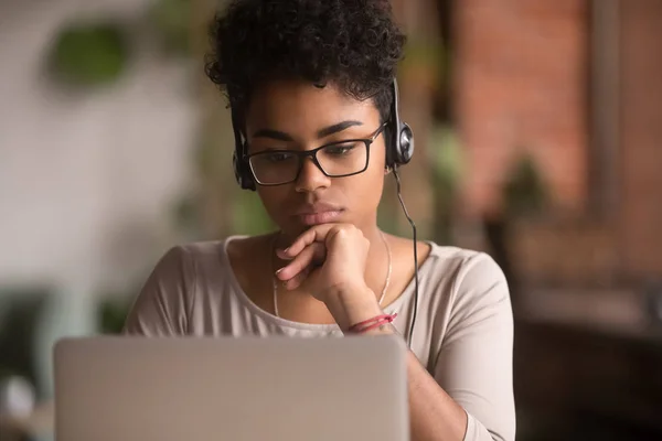 Gericht Afro-Amerikaanse meisje student het dragen van een koptelefoon te kijken naar laptop — Stockfoto