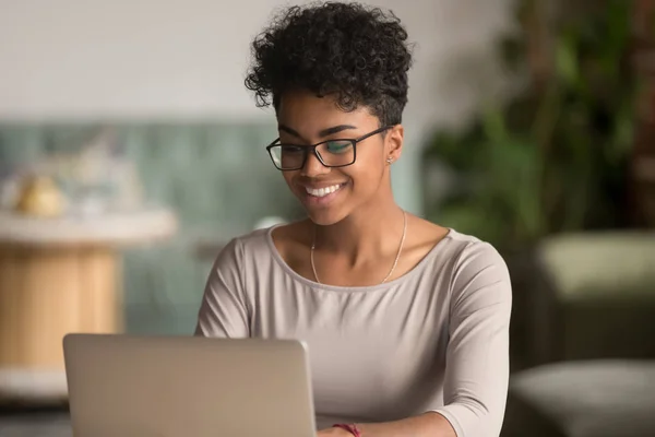 Счастливая американка из Африки, использующая ноутбук для работы в офисе — стоковое фото