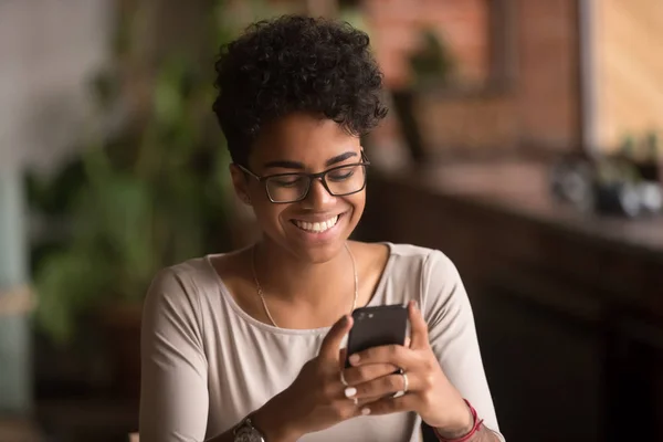 Feliz millennial africana americana mujer sosteniendo teléfono inteligente utilizando aplicaciones de comercio electrónico —  Fotos de Stock