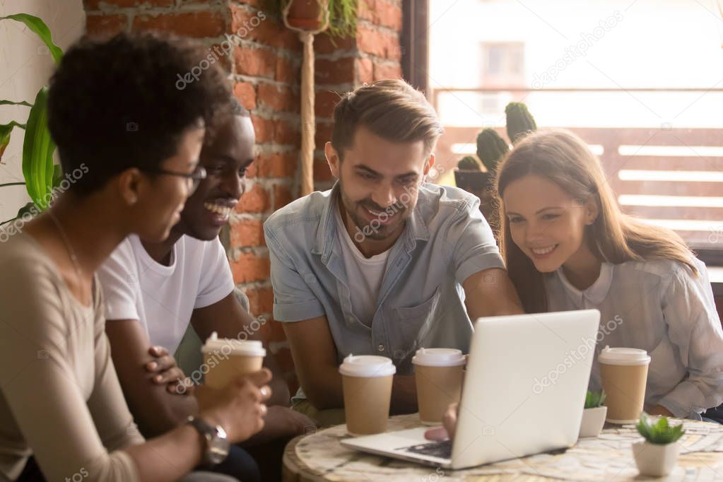 Happy diverse friends group looking at laptop watching comedy movie