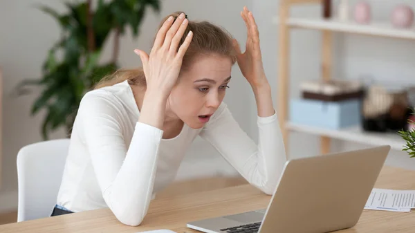 Enojada joven molesta mirando a la computadora portátil, recibiendo malas noticias — Foto de Stock