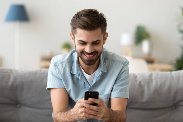 Excited smiling man looking at phone screen, using mobile app