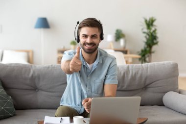 Baş çekim portre mutlu gülümseyen adam içinde kulaklık göstermek thumbs yukarı