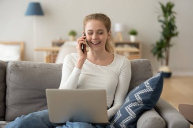 Telefonda konuşan gülüyor kadın, kanepede oturan, laptop kullanarak