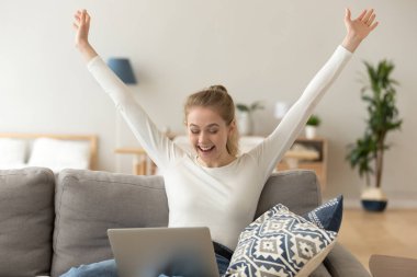 Heyecan gülümseyen kadın online kazanmak kutluyor, evde laptop kullanarak