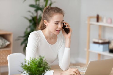 Ciddi kadın laptop kullanarak ve telefon ile müşteri ile konuşan