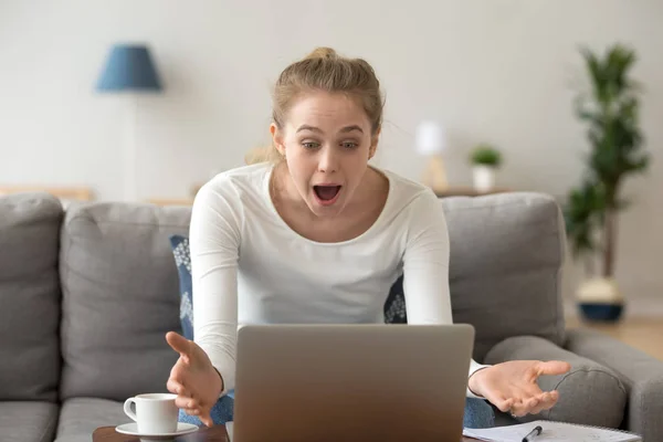 Chockad kvinna med vidöppna ögon tittar på laptop skärm — Stockfoto