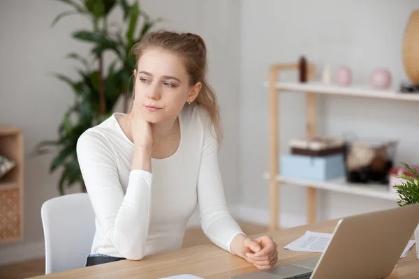 Zamyšlená žena sedící před laptopem, ztracená v myšlenkách — Stock fotografie