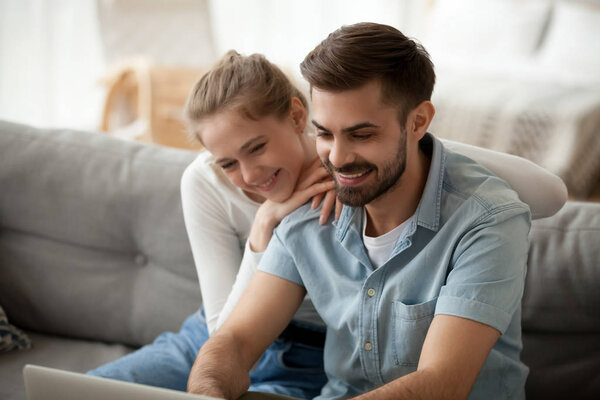 Happy couple spending time together at home, using laptop