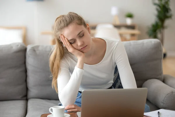 Uttråkad sömnig kvinna som håller huvudet på handen, sitter med laptop — Stockfoto