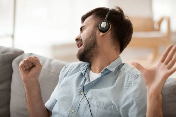Happy man wearing headphones singing song, imagine microphone in hand — Stock Photo, Image