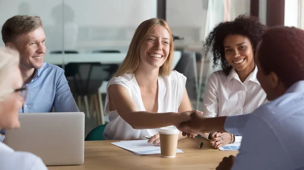 Happy caucasian manager and african client handshaking at group meeting — Stock Photo, Image