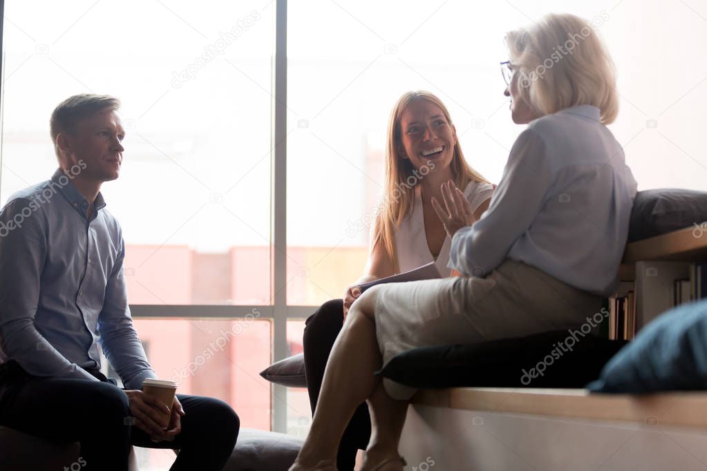 Office workers listening to old woman mentor talking at meeting