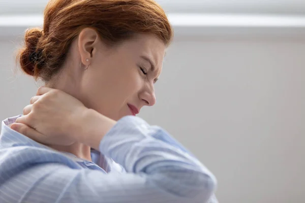 Cansada mulher de negócios fatigada sentindo-se ferida esfregando o pescoço duro — Fotografia de Stock