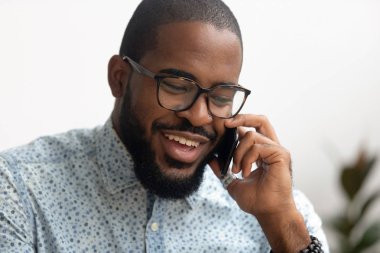 Akıllı telefonla konuşurken gülümseyen Afrikalı Amerikan iş adamı müşteri danışın