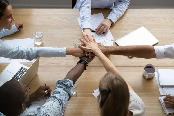 Team people stacking hands together over table engaged in teambuilding — Stock Photo, Image