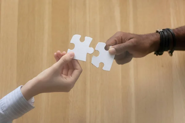 Two diverse male female hands holding join jigsaw puzzle — Stock Photo, Image