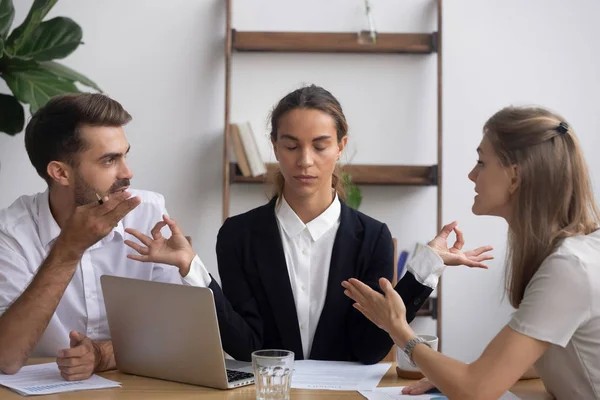 Trabajador estresado meditando en el lugar de trabajo ignorando a colegas discutiendo en la reunión — Foto de Stock