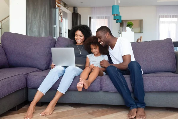 Familia afroamericana feliz con hija usando portátil en casa — Foto de Stock