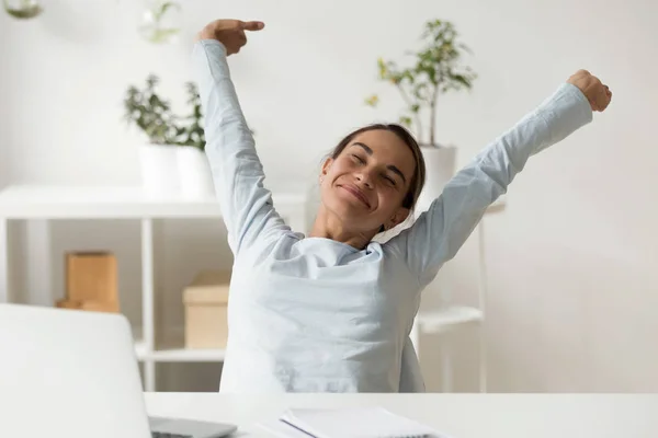 Happy woman stretching in front of desk at work — Stock Photo, Image