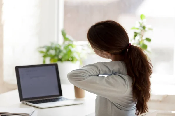 Back view of tired woman touching neck at work desk — Stock Photo, Image