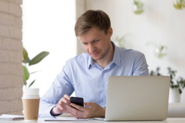 İşyerinde akıllı telefon kullanan gülümseyen işadamı