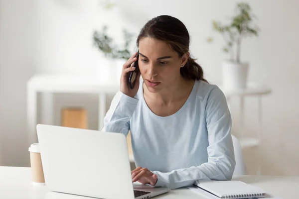 Mujer de negocios seria hablando por teléfono trabajando en el ordenador portátil — Foto de Stock