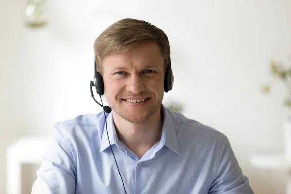 Retrato del hombre guapo sonriente trabajando en auriculares en la oficina —  Fotos de Stock