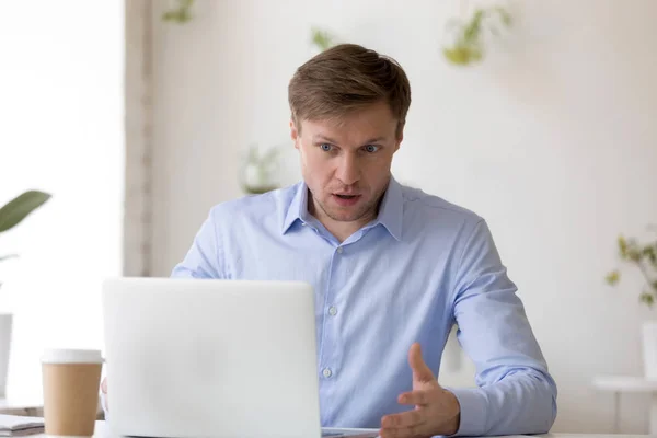 Empresário olha para a tela do laptop com expressão de surpresa — Fotografia de Stock