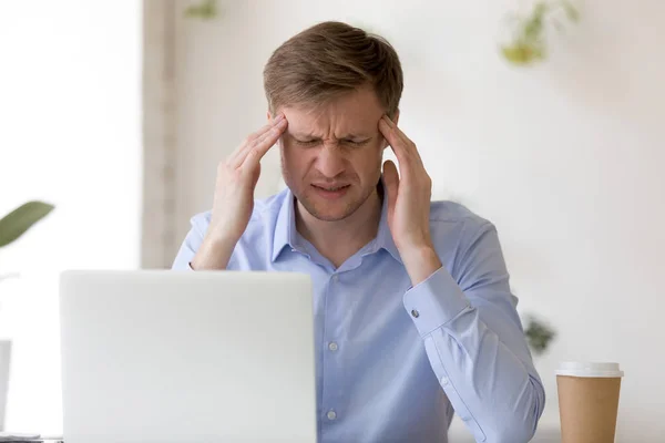 Hombre tocando templos tratando de centrarse teniendo dolor de cabeza en el trabajo — Foto de Stock