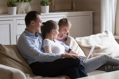 Evde kanepede dinlenen aile bilgisayarda film izlerken