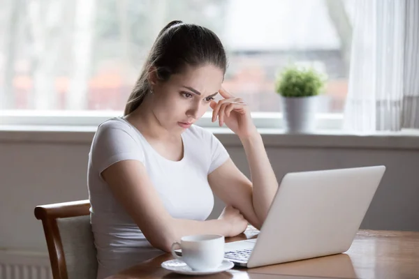 Розчарована жінка дивиться на екран комп'ютера, читаючи погані новини — стокове фото