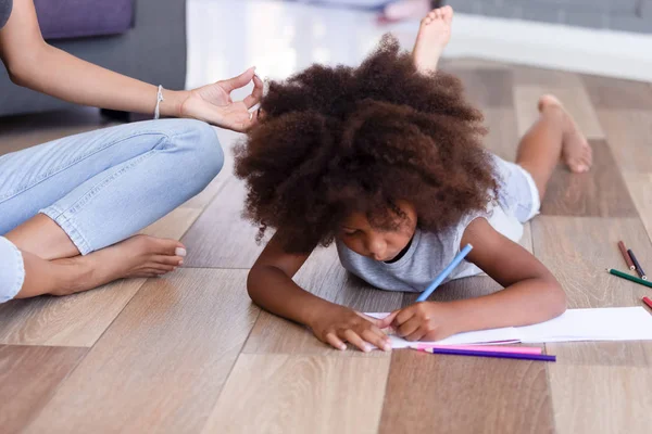 Bastante afroamericana chica dibujo lápices mientras madre meditando — Foto de Stock