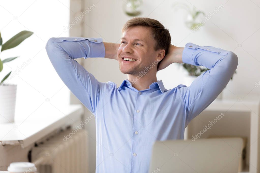 Man daydreaming with happy smile with hands clasped behind head