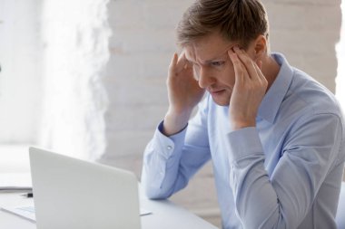 İş yerinde baş ağrısı olan odaklanmaya çalışan tapınaklara dokunan adam